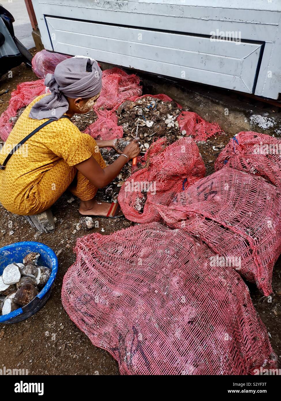 A Comoran woman sorting Yams at the Moroni market. - Smartphone Captured Stock Image