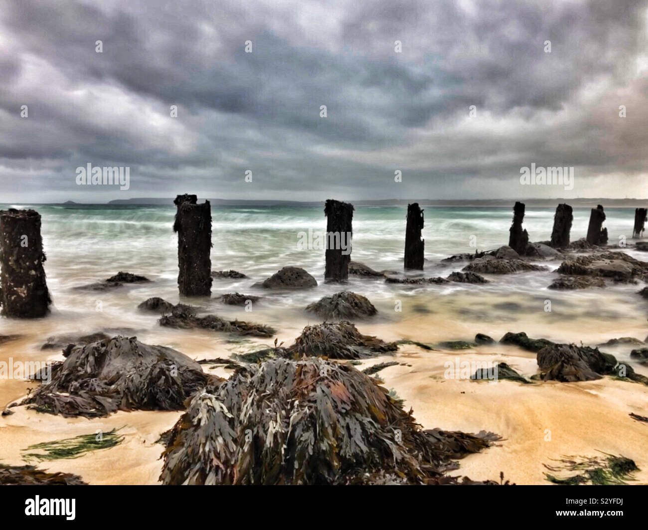 Rough seas and heavy cloud over old wooden groynes at St Ives, Cornwall, England, October. - Smartphone Captured Stock Image