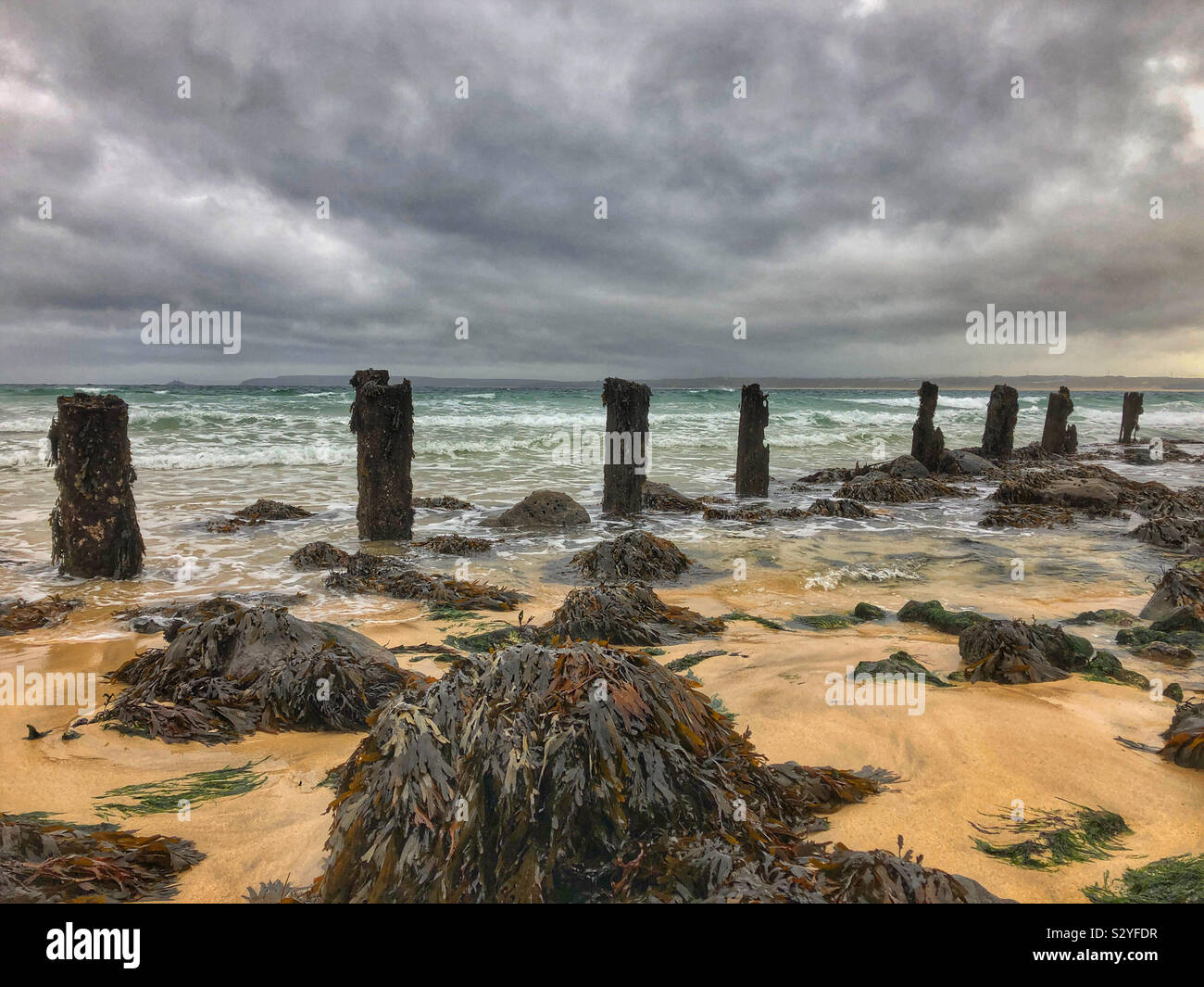 Waves washing over old wooden groynes in bad weather at St Ives, Cornwall, October. - Smartphone Captured Stock Image
