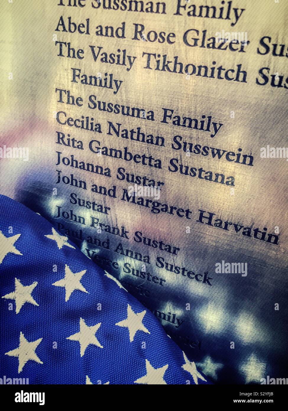 Close up of an American flag reflected in the wall of honor at the Ellis Island national