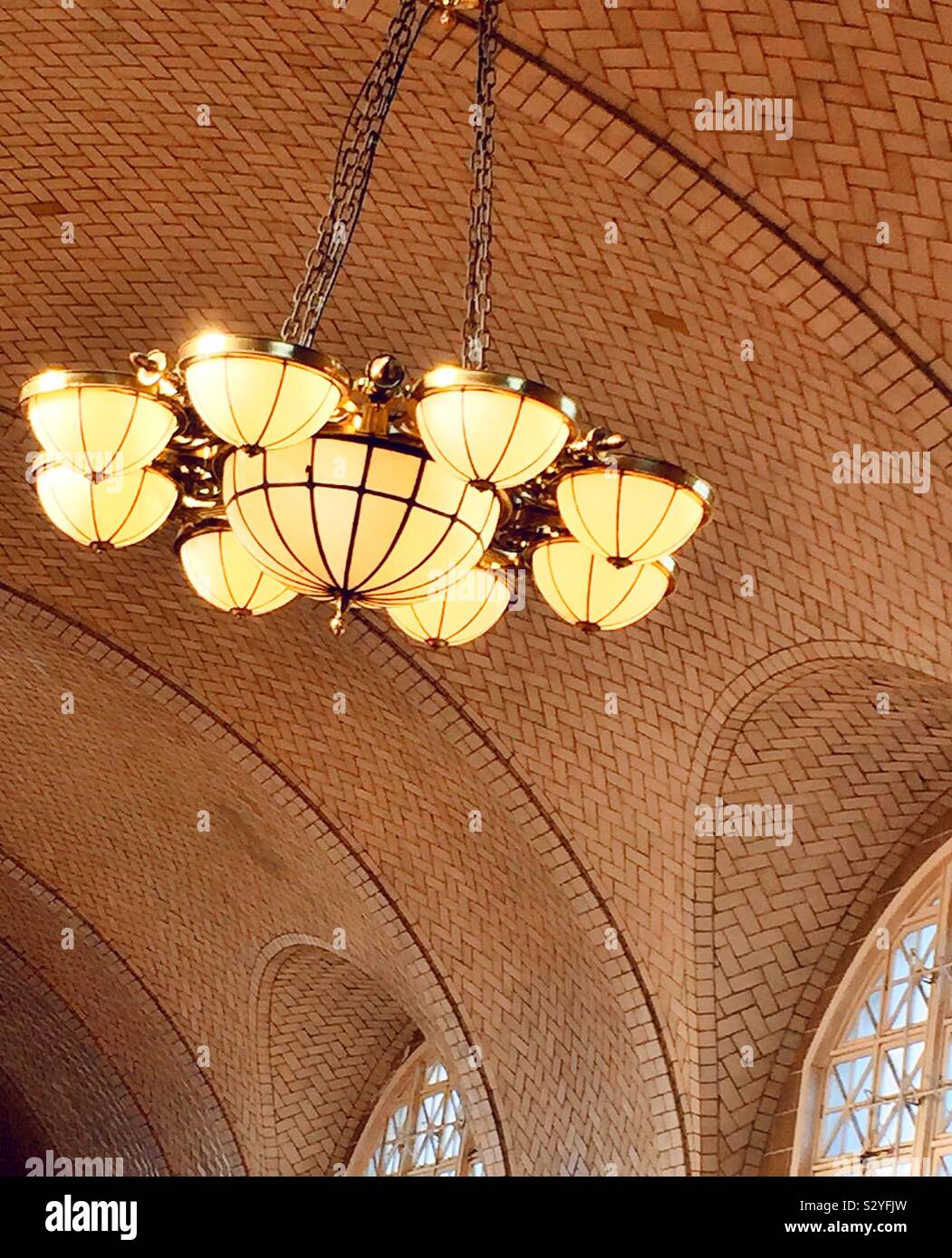 Ornate chandelier suspended from the vaulted ceiling in the giant registry hall at the Ellis Island national Memorial, NYC, USA - Smartphone Captured Stock Image