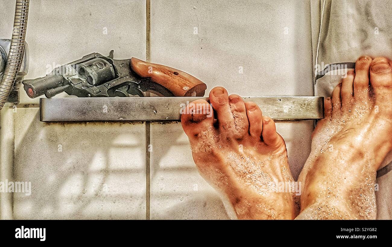 Revolver with shadow on metal shelf above bathtub with man’s crossed feet - Smartphone Captured Stock Image