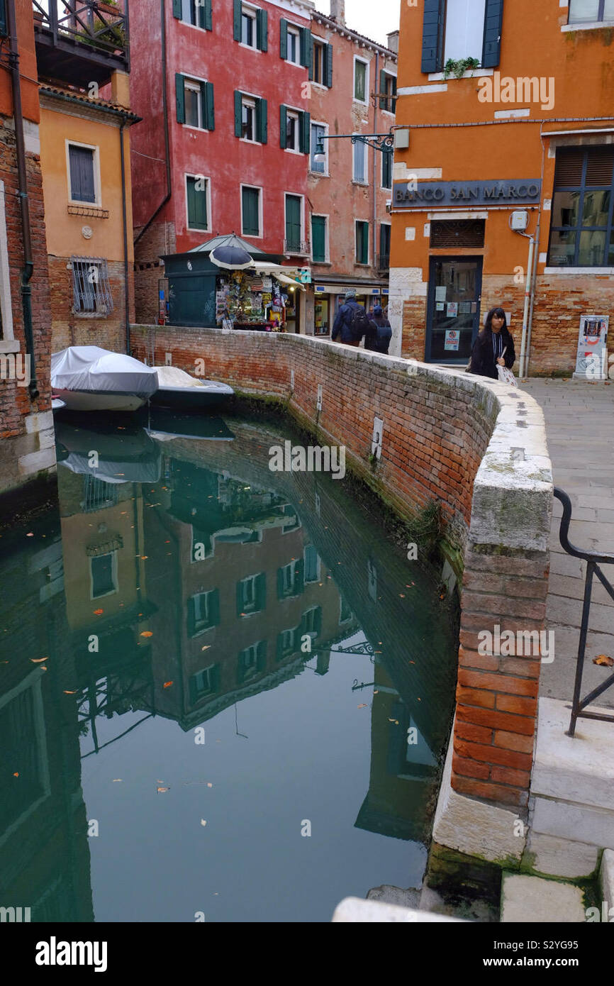 Typical scene of a canal in Venice with colourful buildings and a boat - Smartphone Captured Stock Image