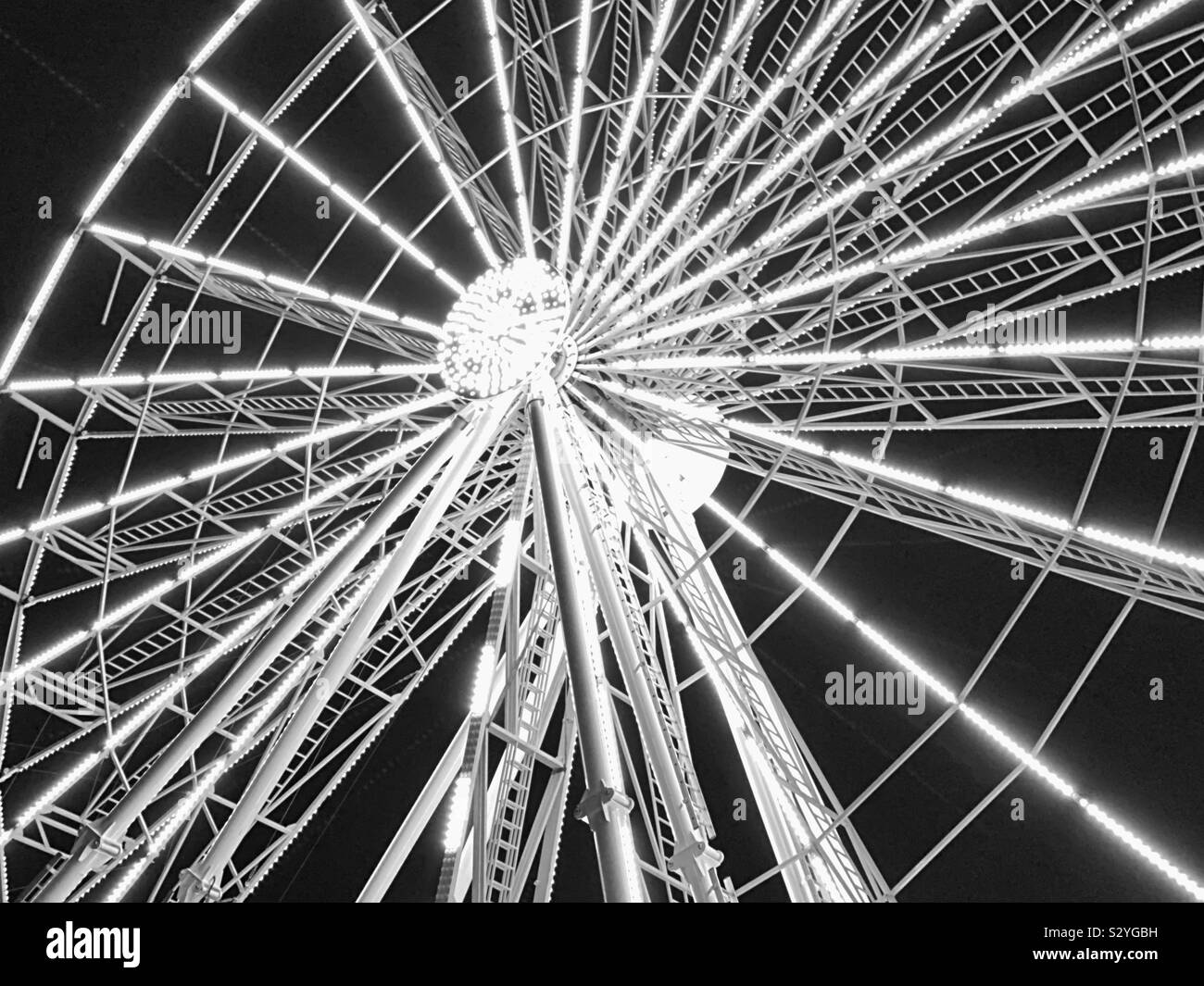 Giant Ferris wheel illuminated in white light against a black night sky - Smartphone Captured Stock Image
