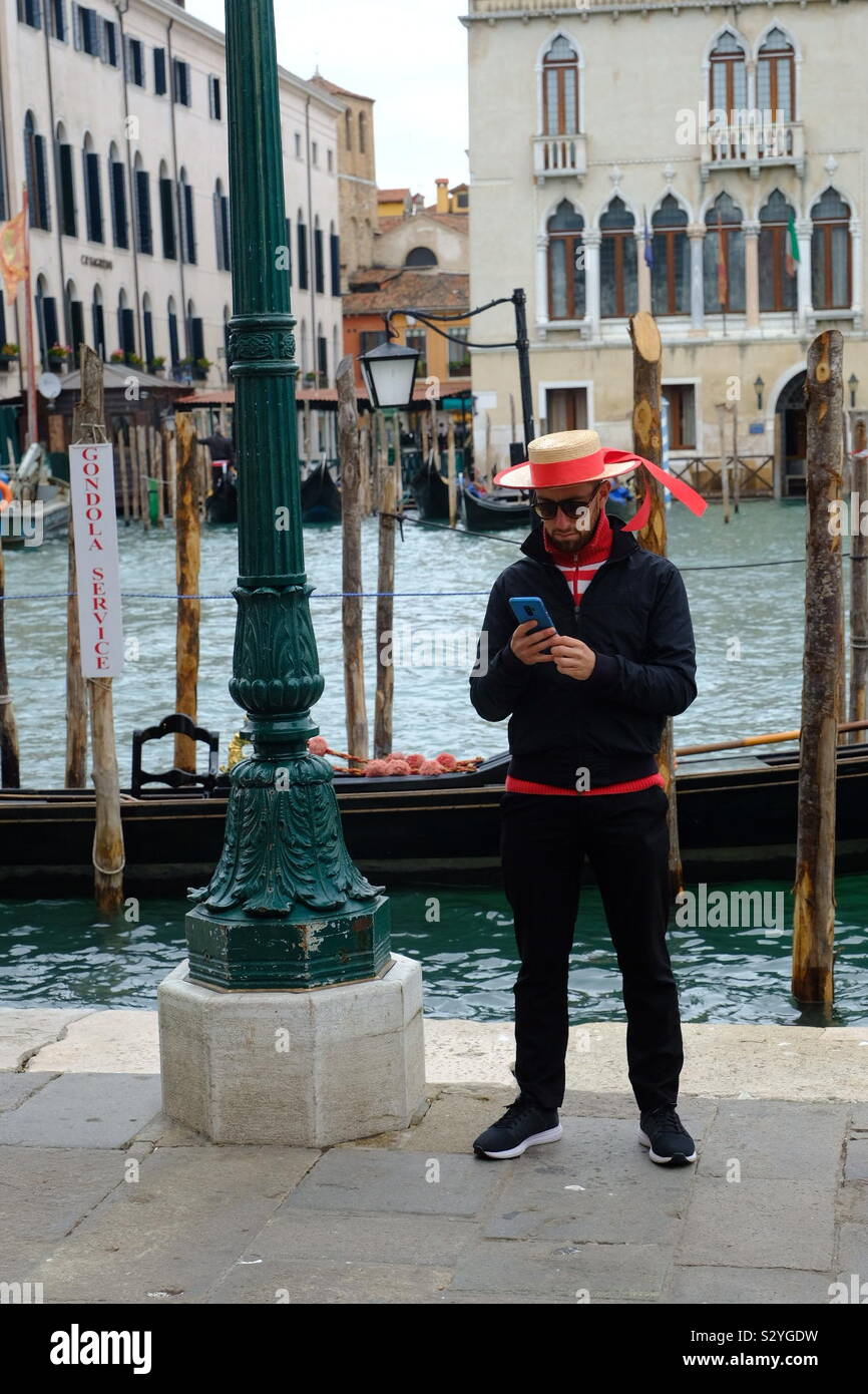Gondolier on his smartphone as he waits for a client Stock Photo