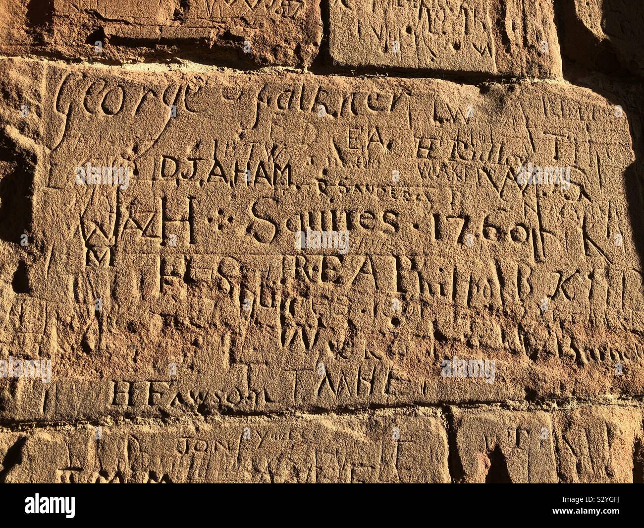 Graffiti from the 18th and 19th Century on the walls of Kenilworth Castle brilliantly lit in winter sunshine. Stock Photo