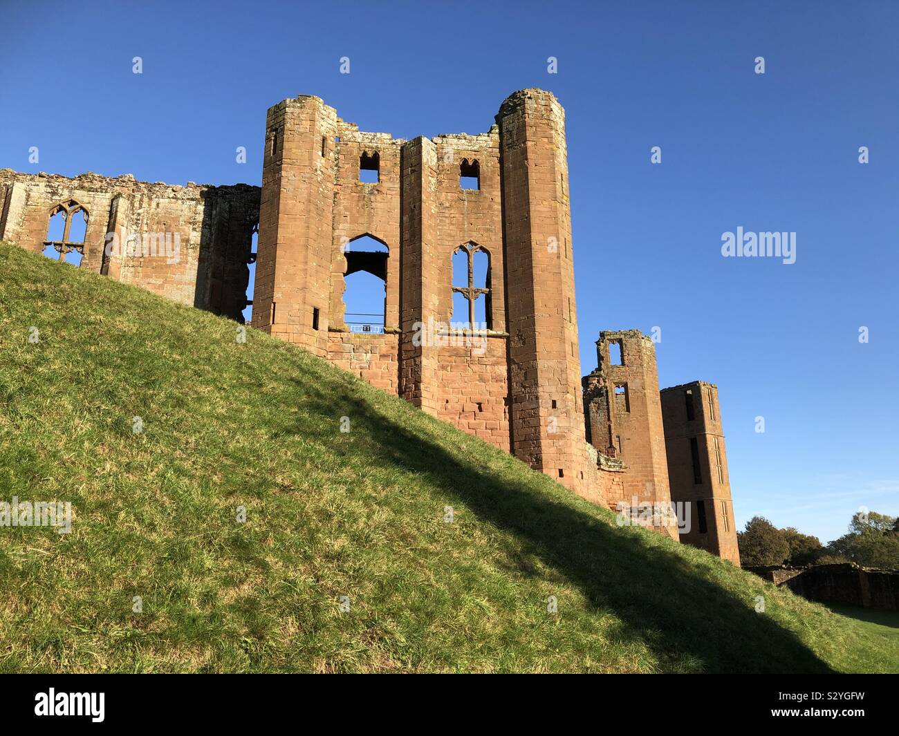 Ruins at Kenilworth Castle brilliantly lit against a perfect blue sky. Stock Photo
