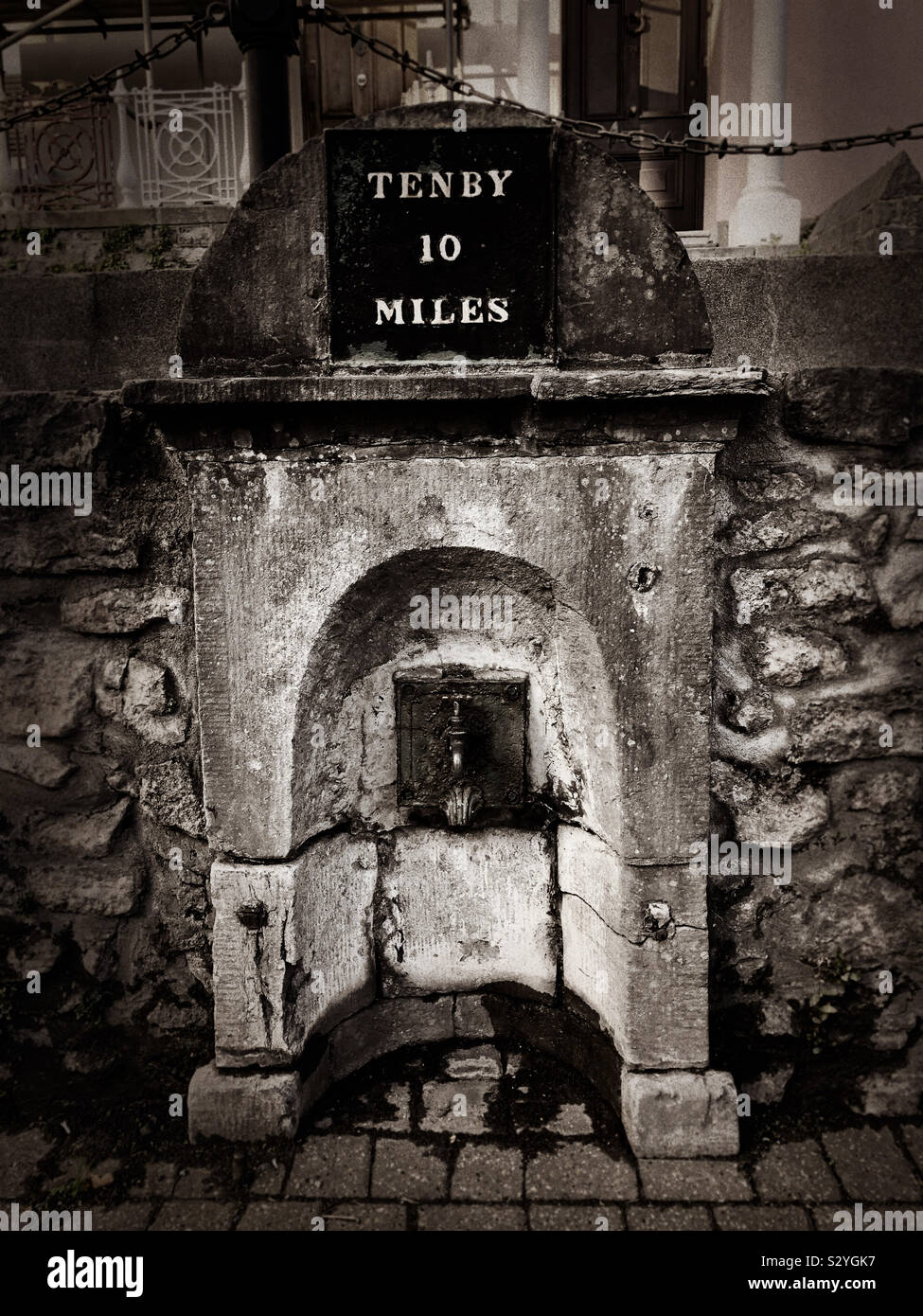An old water trough  in Pembroke, Pembrokeshire, Wales, UK with milestone to Tenby. - Smartphone Captured Stock Image