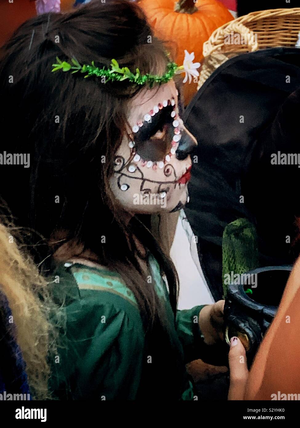 A young girl with a face painted like a catrina waits for her turn for candy while trick or treating on Halloween in Ajijic, Mexico. Stock Photo