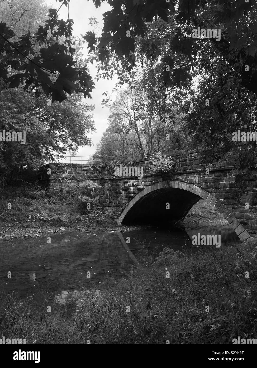Arched stone bridge over river in black and white. Stock Photo