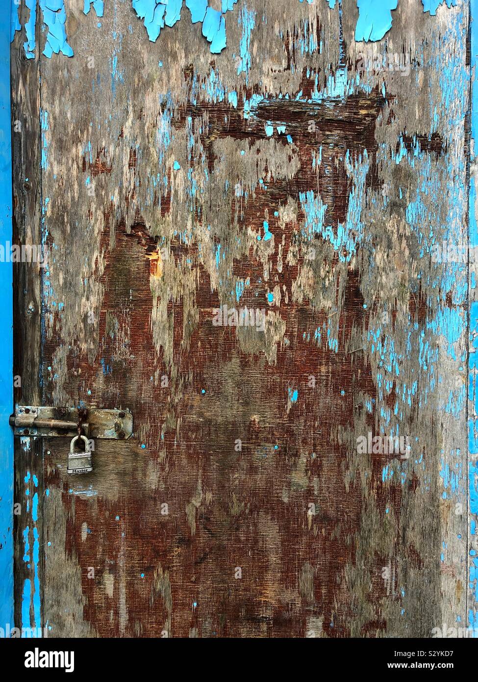 Old wooden door with shades of brown and blue peeling paint - Smartphone Captured Stock Image
