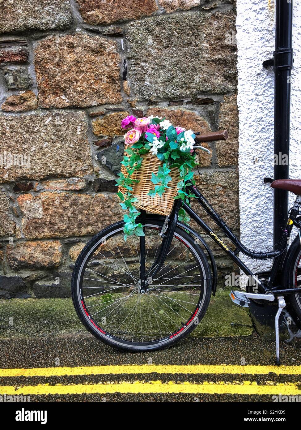 Bicycle parked against a wall on double yellow lines. Stock Photo