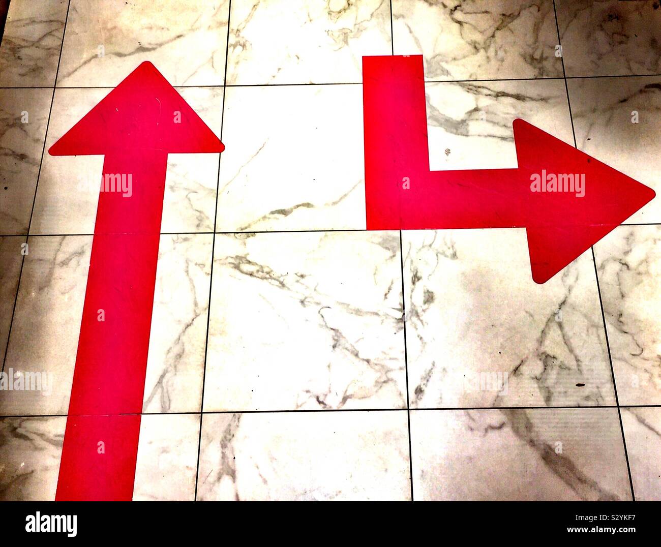 Arrows pointing in different directions on a tile floor - Smartphone Captured Stock Image