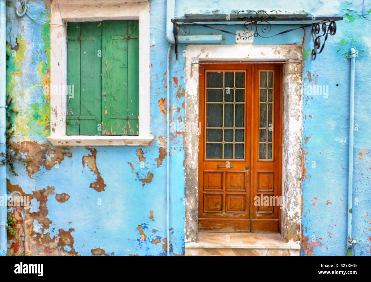 A colourful wall with peeling paint and window and door - Smartphone Captured Stock Image