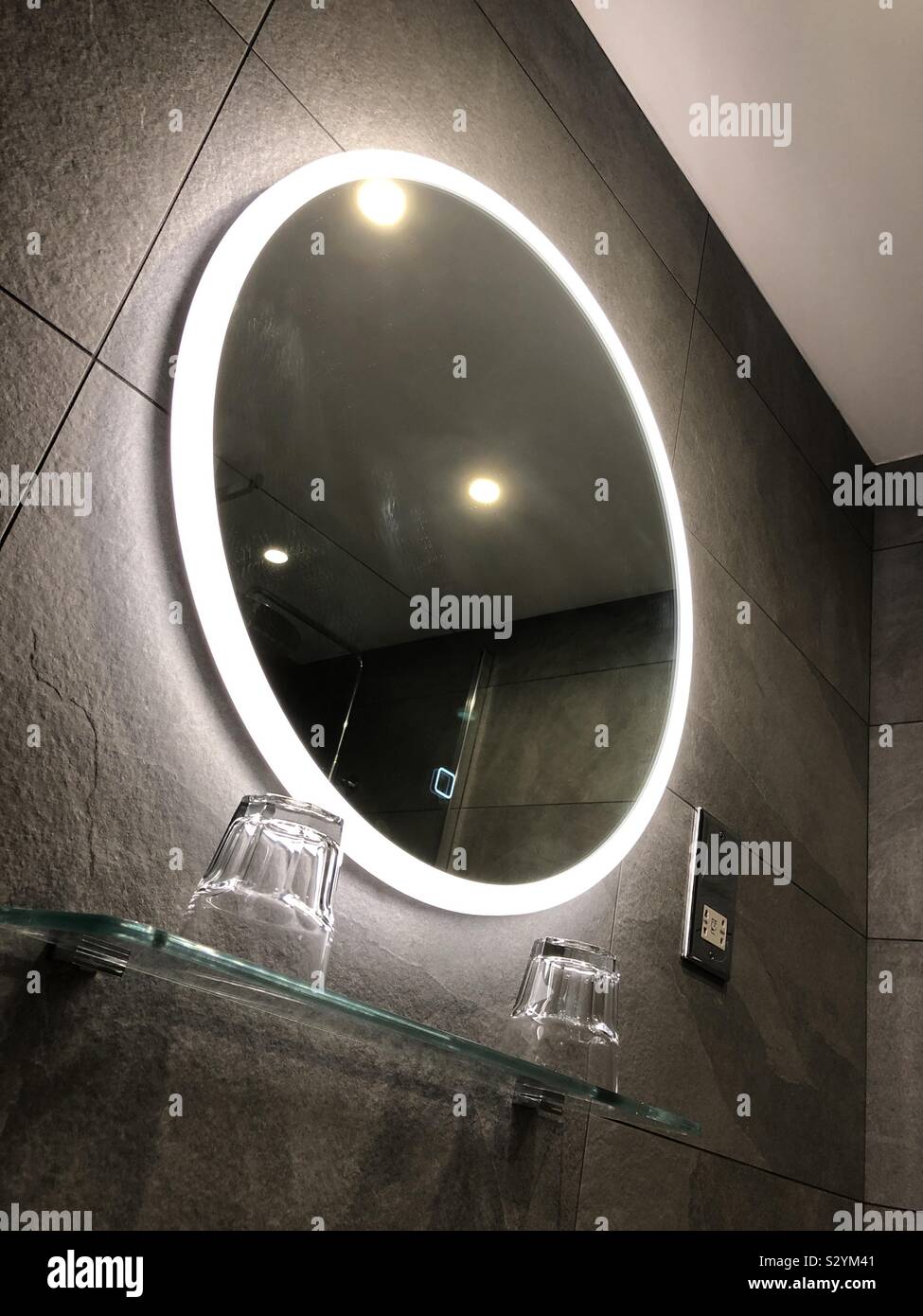 Modern bathroom with an LED heated mirror and grey tiled walls, United Kingdom - Smartphone Captured Stock Image