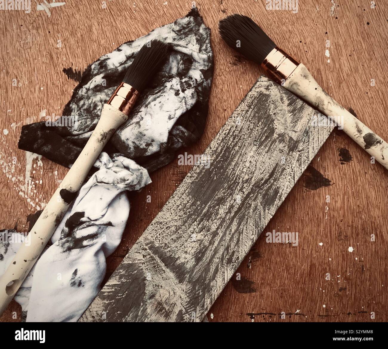 Chalk paint brushes, rags and a painted piece of pallet wood. Stock Photo