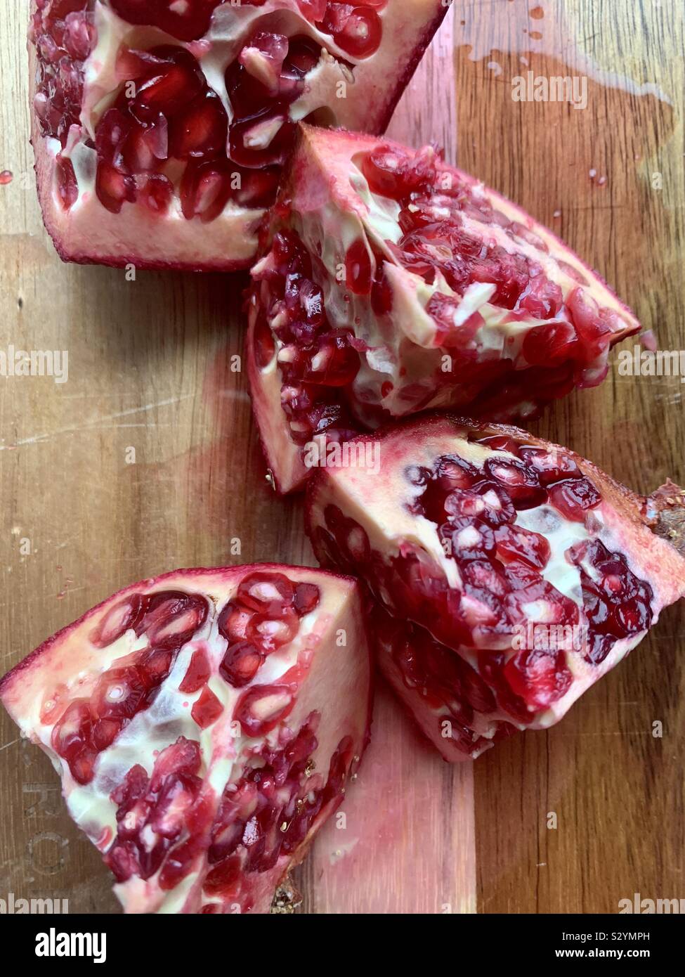 Cut juicy pomegranate on a cutting board - Smartphone Captured Stock Image