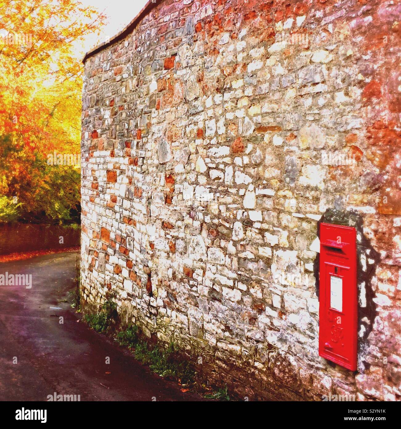 A traditional red letter box, set into a wall on a rural lane Stock Photo