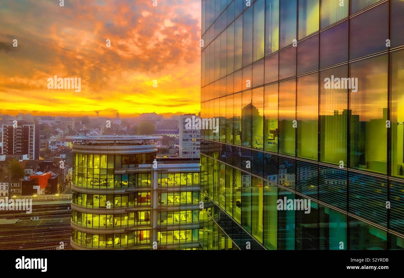 Dramatic and colorful sunrise sky over the city streets and reflected in the glass windows of a business office building - Smartphone Captured Stock Image
