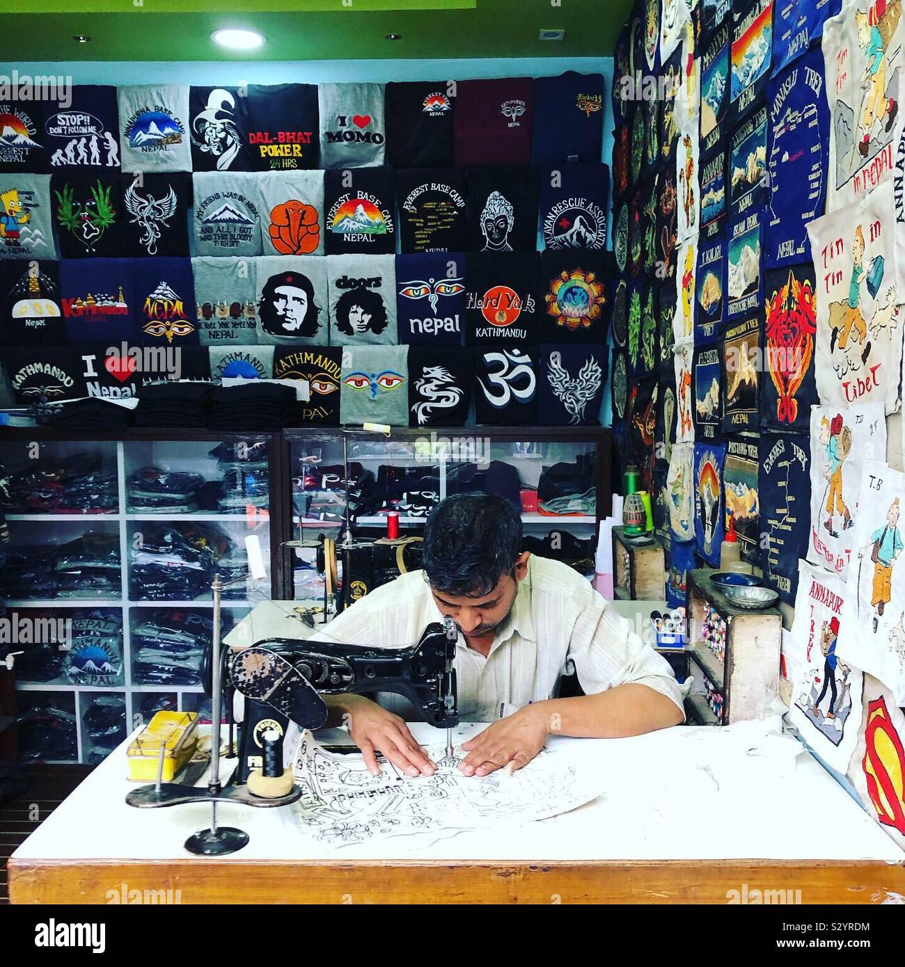 A t-shirt artist at work behind his sewing machine in Kathmandu, Nepal. - Smartphone Captured Stock Image