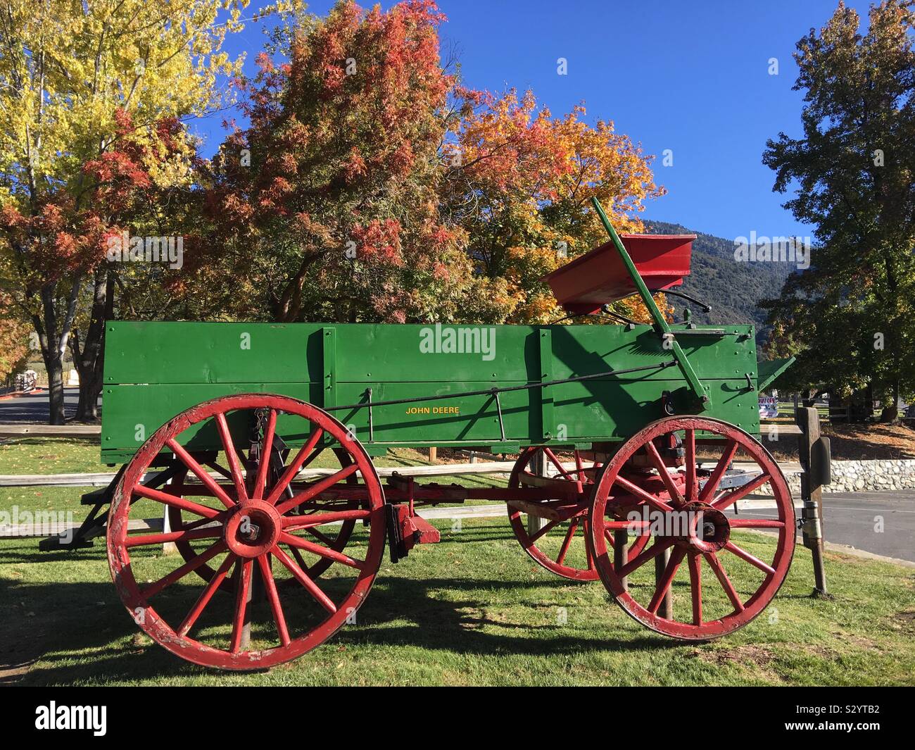 John Deere antique wooden farm wagon with scenic fall leaves at Oak Glen Preserve in San Bernardino County USA Stock Photo