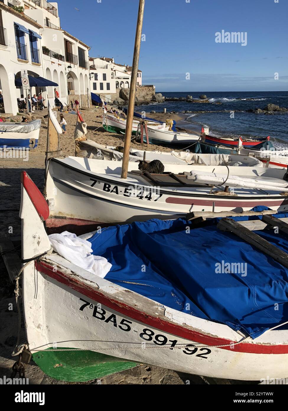 Traditional fishing boats resting on Canadell beach in Calella de Palafrugell in Costa Brava, Spain, in November sunshine. - Smartphone Captured Stock Image