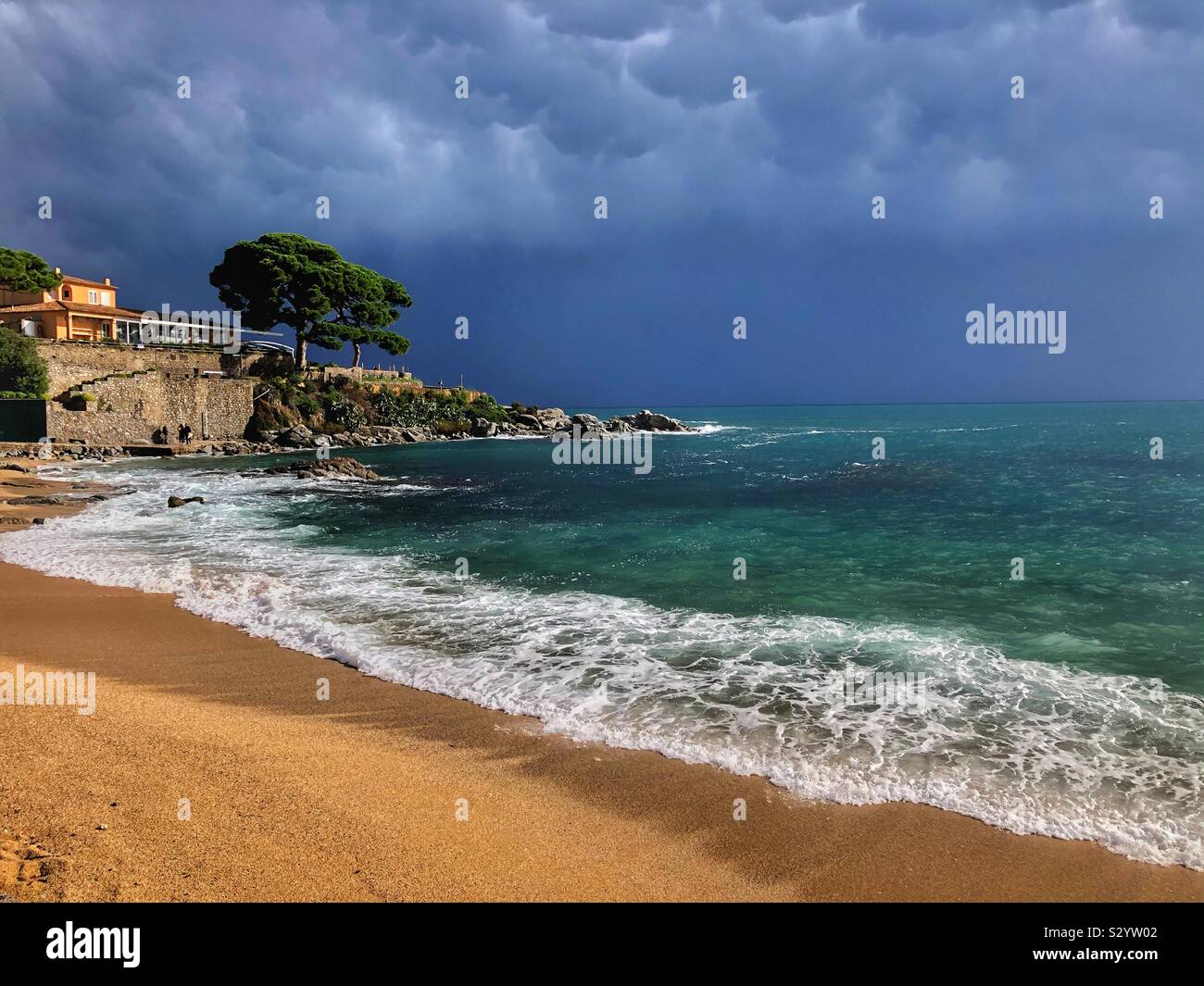 Dramatic rain clouds moving offshore into the Mediterranean Sea and leaving sunshine over Canadell beach, Costa Brava in Spain. - Smartphone Captured Stock Image