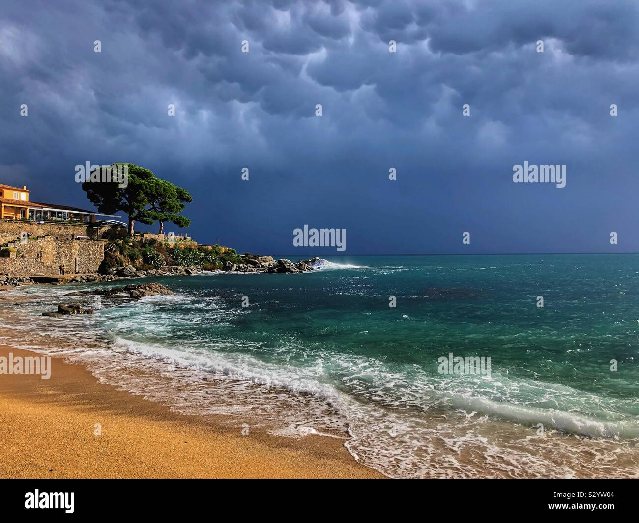 Dramatic rain clouds moving offshore into the Mediterranean Sea and leaving sunshine over Canadell beach, Costa Brava in Spain. - Smartphone Captured Stock Image