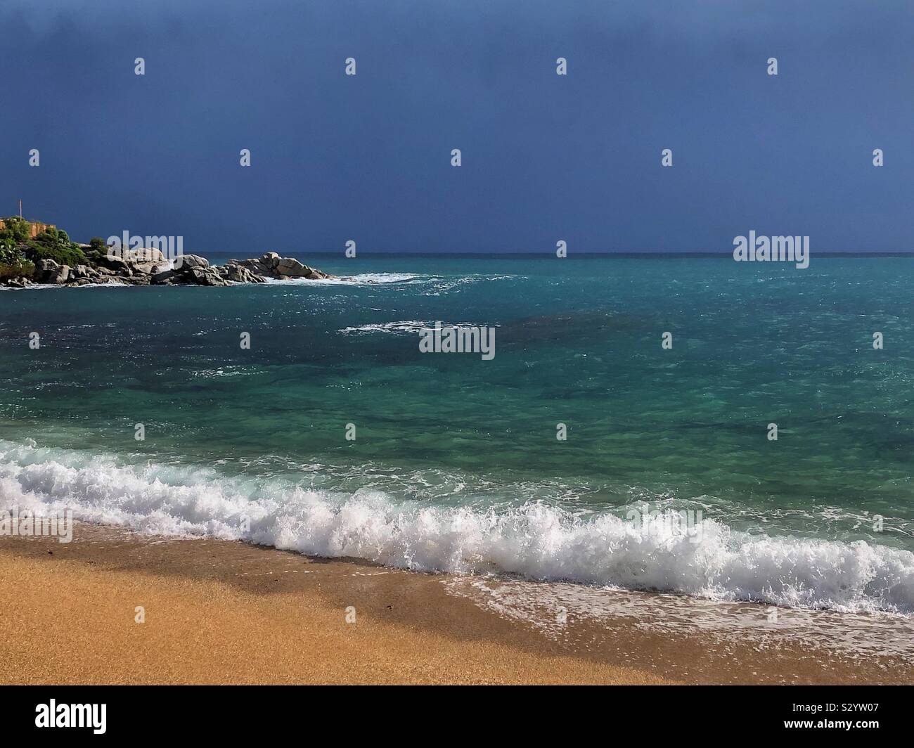 Dramatic rain clouds moving offshore into the Mediterranean Sea and leaving sunshine over Canadell beach, Costa Brava in Spain. - Smartphone Captured Stock Image