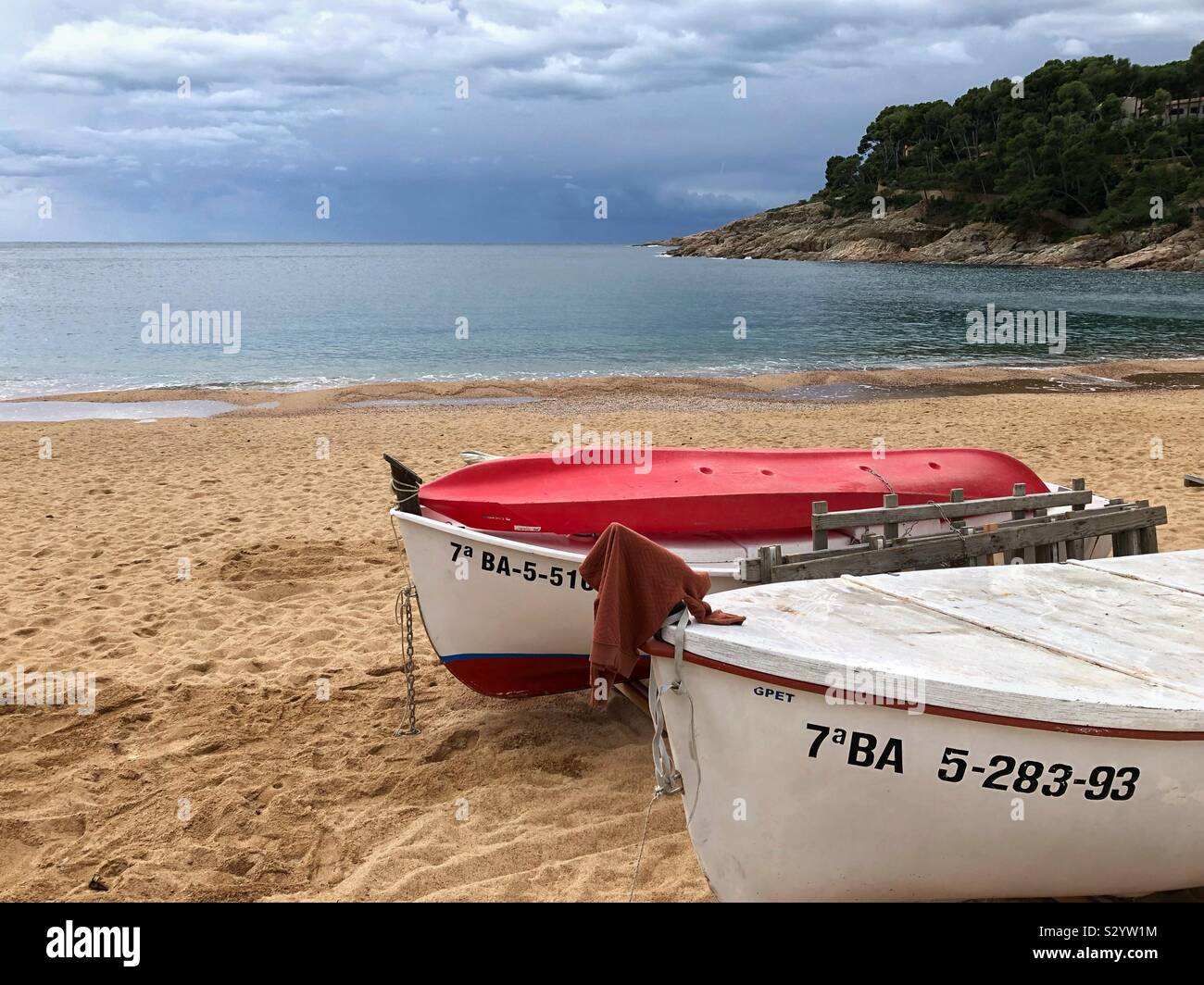 Two fishing boats moored side by side on the beach in Llafranc on a wet November day, Costa Brava, Spain. - Smartphone Captured Stock Image
