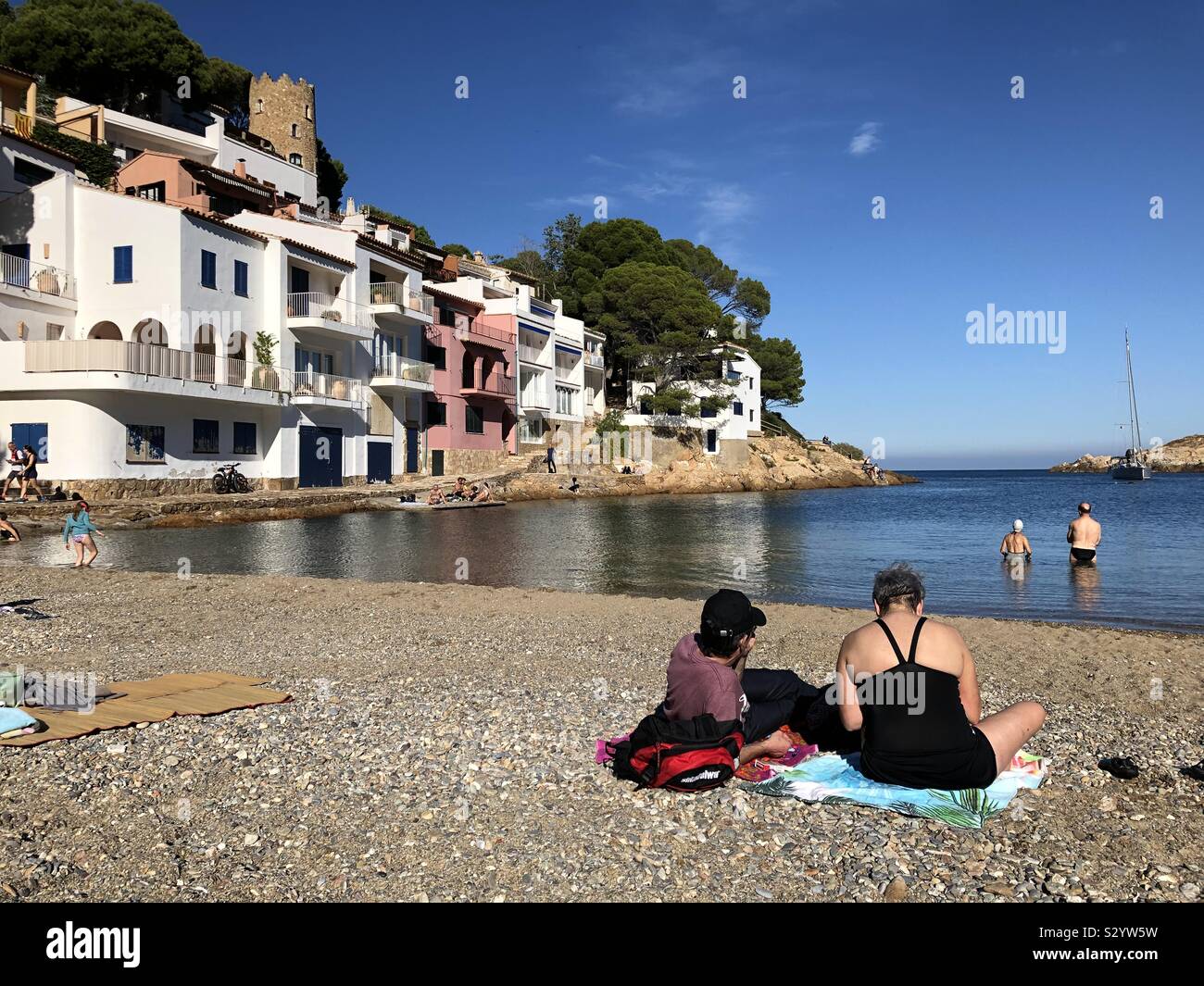 Sunbathers and swimmers at Sa Tuna beach near Begur on Costa Brava, Spain, on a sunny and warm November day. - Smartphone Captured Stock Image