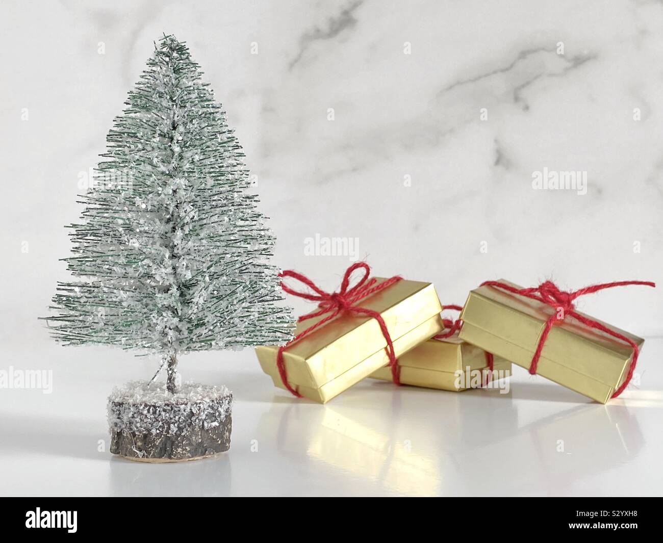 Miniature Christmas tree with gold gift boxes tied with red jute - Smartphone Captured Stock Image