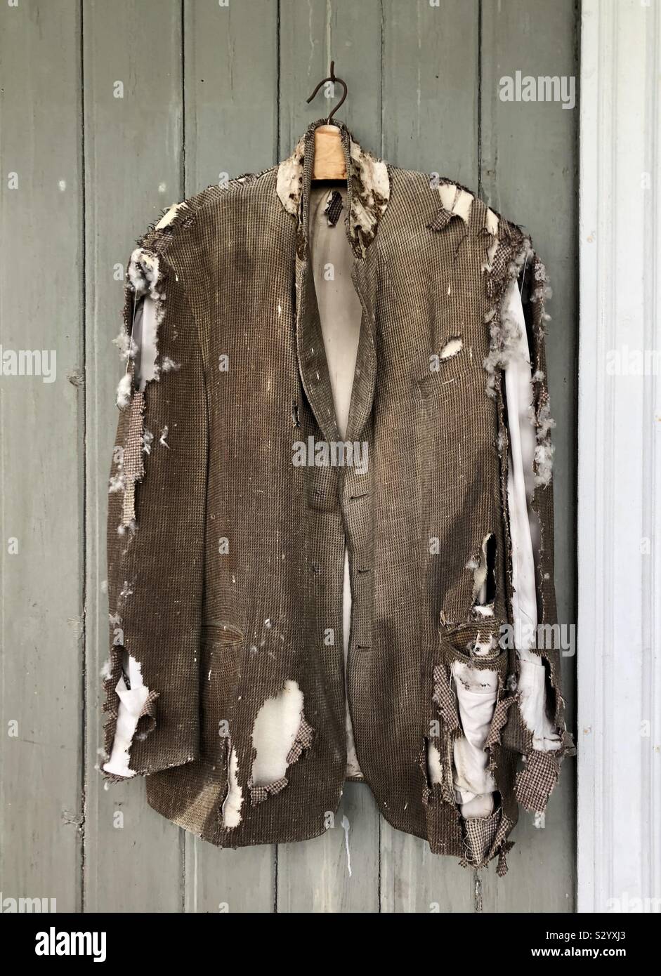 An old jacket disintegrating on its clothes hanger as it has been left exposed for about fifty years. - Smartphone Captured Stock Image