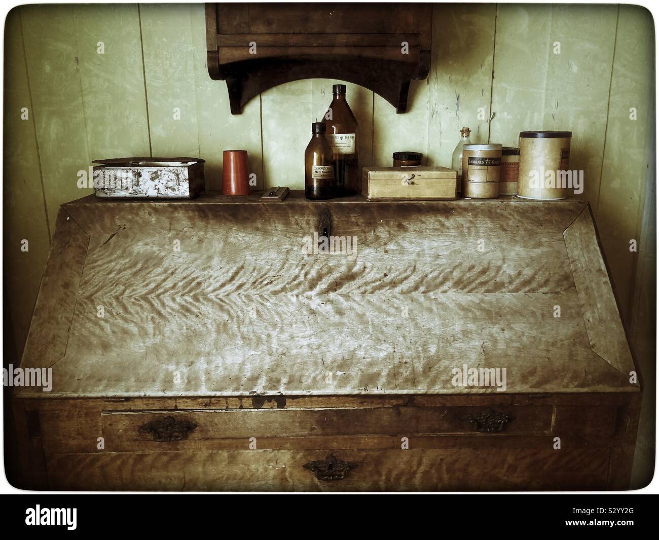 Old bureau with tins and expired medicine bottles placed on top of it. - Smartphone Captured Stock Image