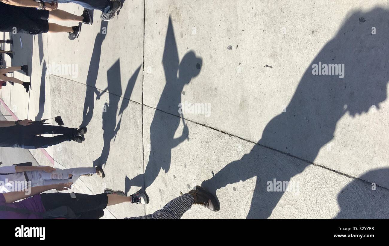 LOS ANGELES, CA, AUG 2019: Shadows of anonymous striking workers with picket signs, seen on concrete sidewalk on a sunny day - Smartphone Captured Stock Image