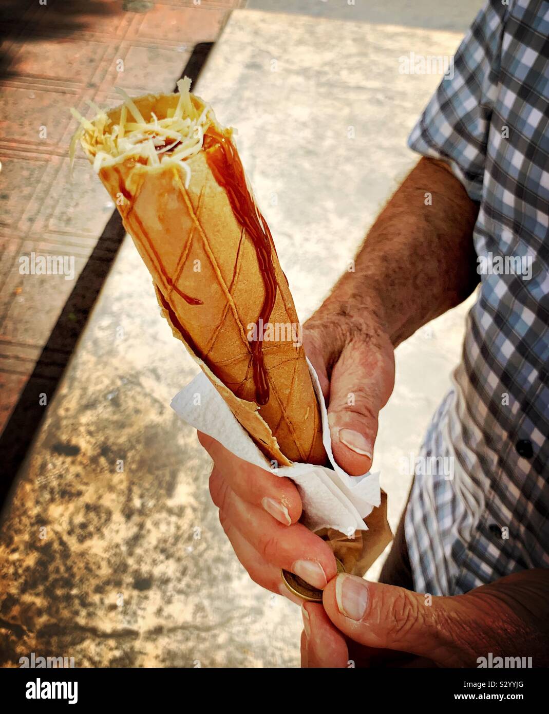 A man holds a sweet and savory Marquesita, a crunchy filled crepe like snack that originated in Mérida. Stock Photo