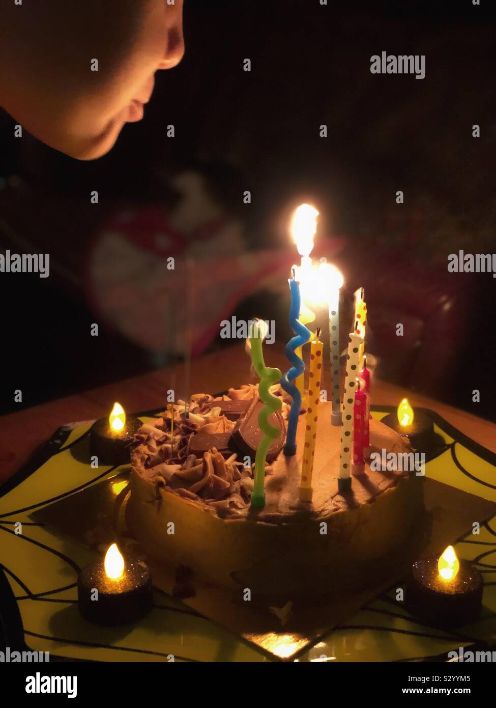 Boy blowing out candles on a birthday cake Stock Photo