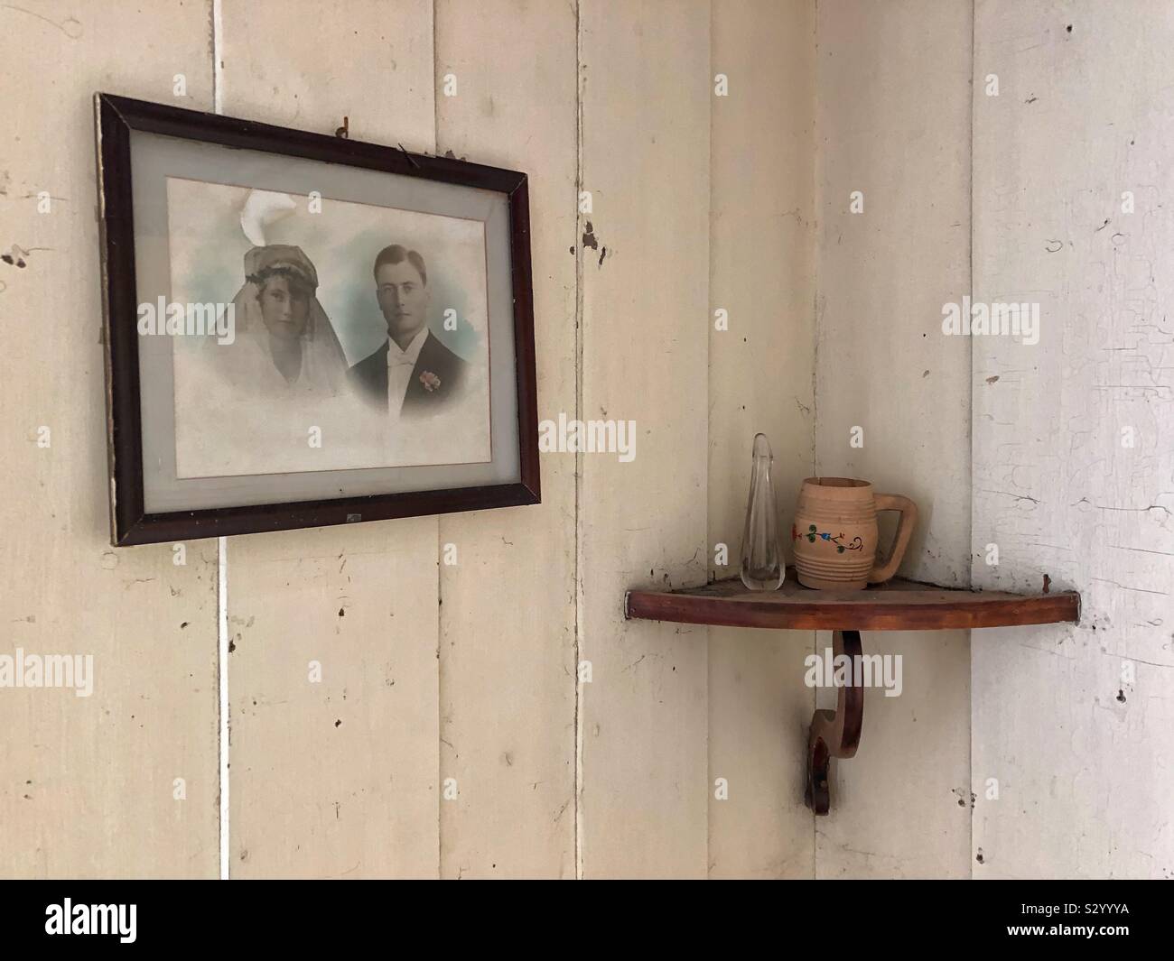Interior wood panelled wall with framed portraits photo and  corner shelf in old abandoned farmhouse. - Smartphone Captured Stock Image
