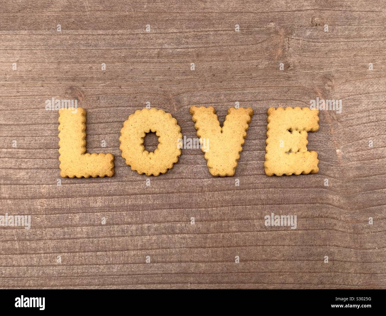Love word composed with biscuit letters on a wooden board Stock Photo