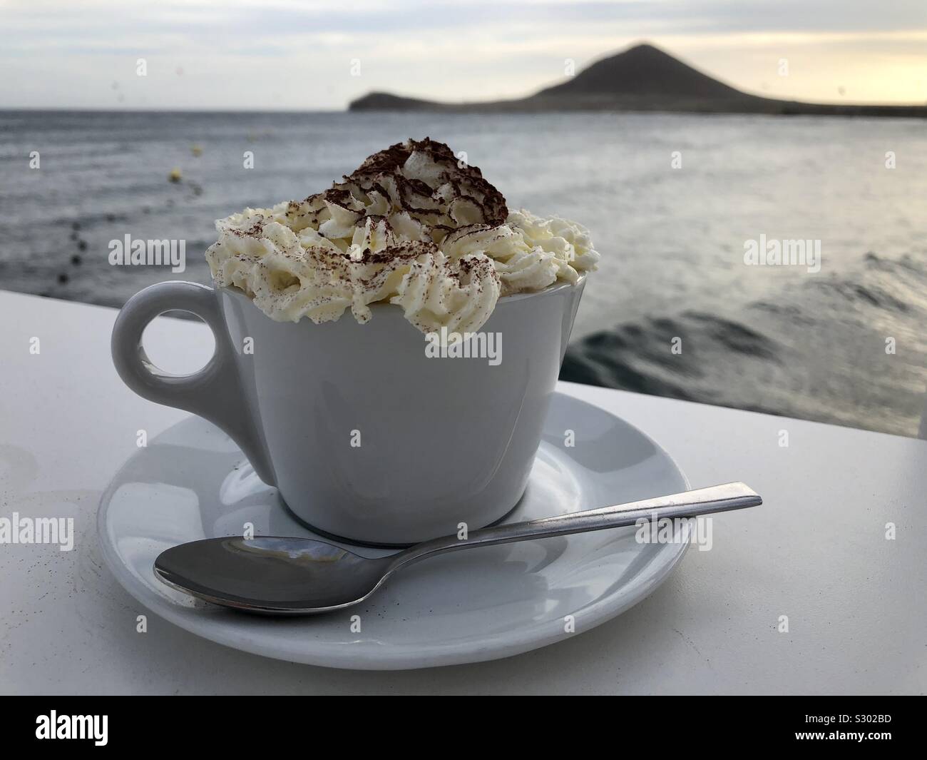 Tasse Cappuccino mit Sahne mit Ausblick auf den Atlantik in der Ortschaft El Medano/Teneriffa Stock Photo