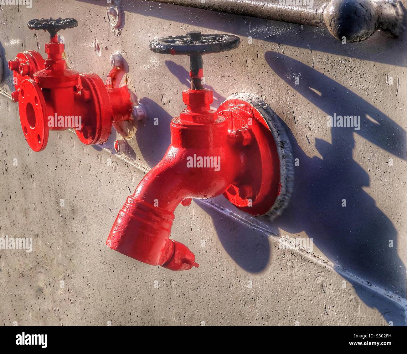 Wall mounted red painted water taps , Scotland, UK - Smartphone Captured Stock Image