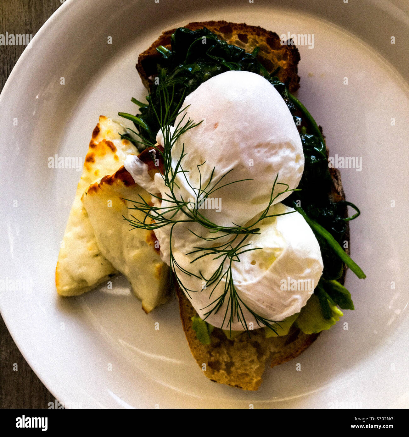 Poached eggs for breakfast on sourdough toast with Halloumi and spinach Stock Photo Alamy