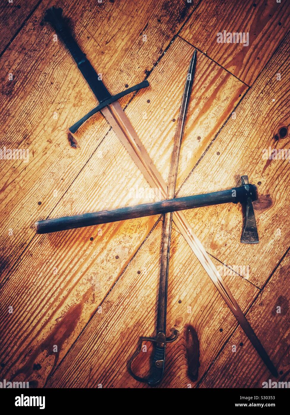Two swords and a battle ax arranged on wooden plank background - Smartphone Captured Stock Image