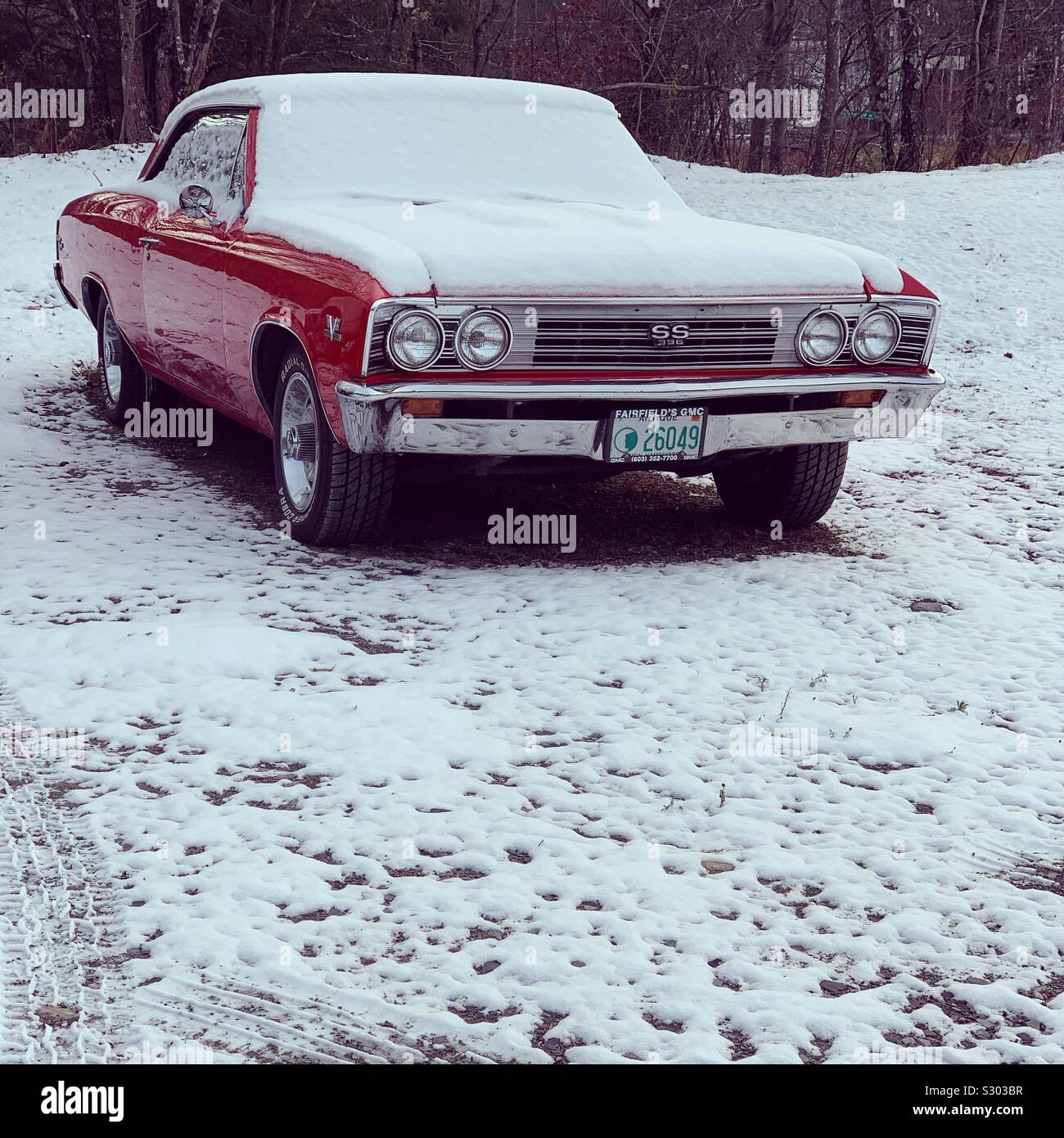 A red antique car under a light dusting of snow in Vermont, United States - Smartphone Captured Stock Image