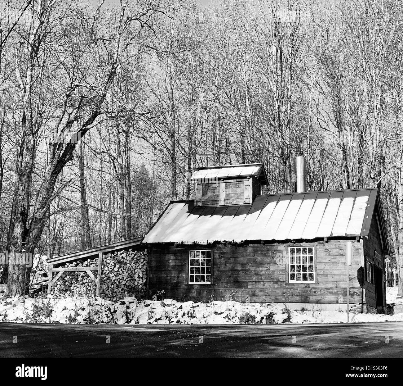 Black and white image of a small building in a snowy landscape near the road, Warren, Vermont, United States - Smartphone Captured Stock Image