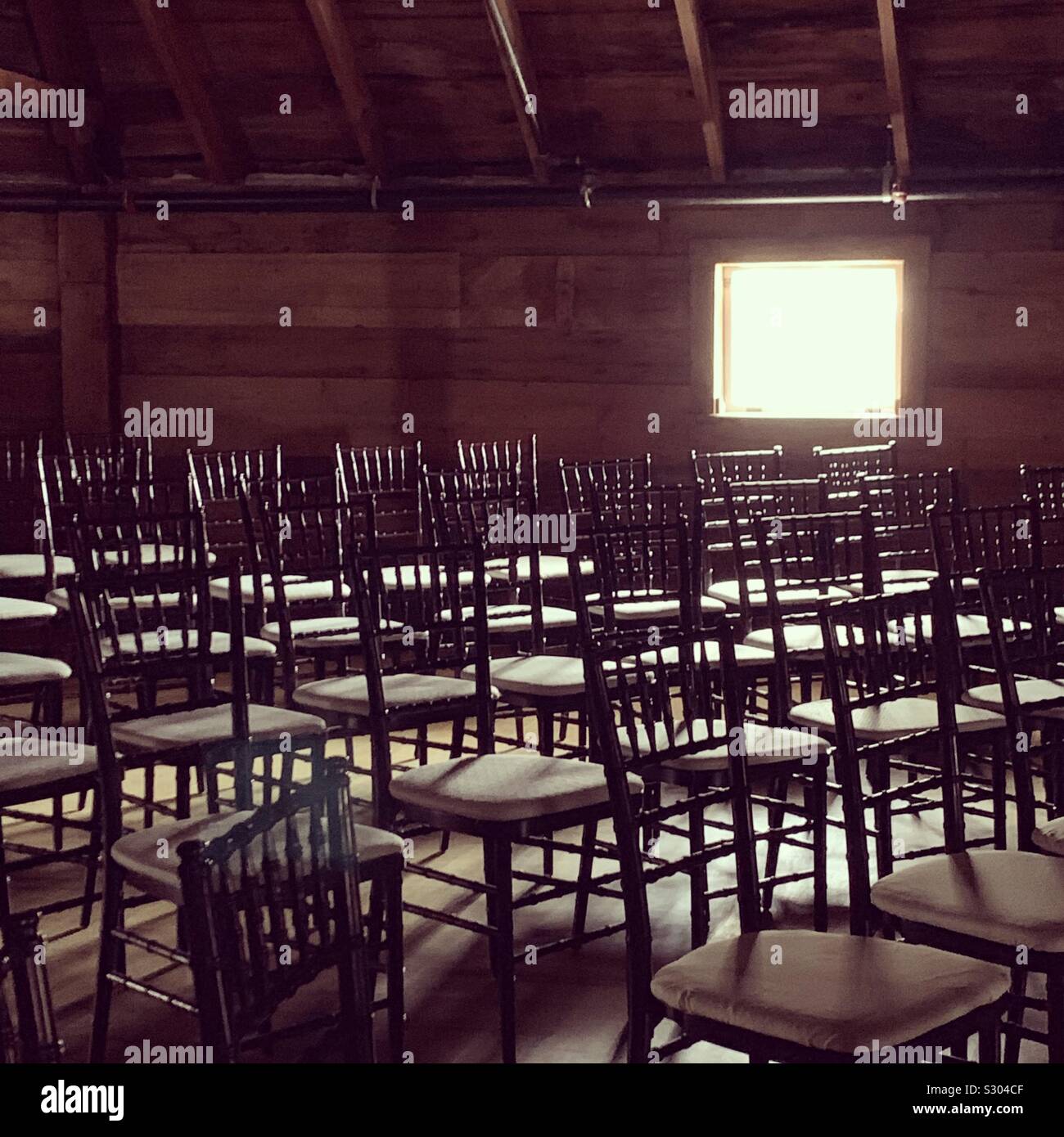 Light from a small window illuminates rows of chairs - Smartphone Captured Stock Image