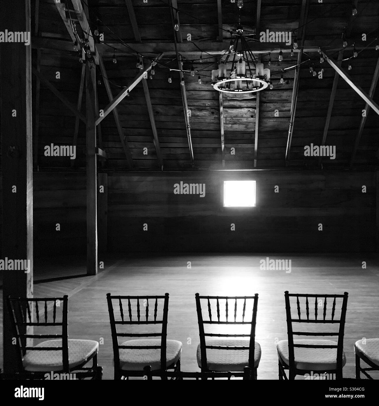 Light from a small window falls upon a row of chairs under a vaulted ceiling - Smartphone Captured Stock Image