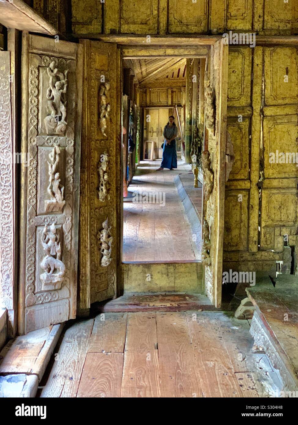Golden palace made of teak wood looking down a long hallway with open doors - Smartphone Captured Stock Image