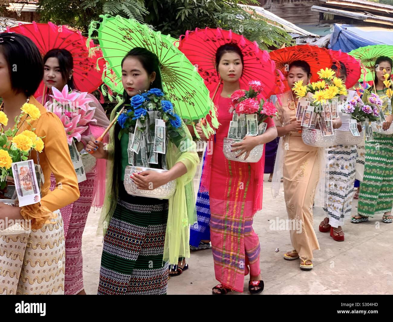 Beautiful Burmese women with colorful umbrellas and gifts of flowers