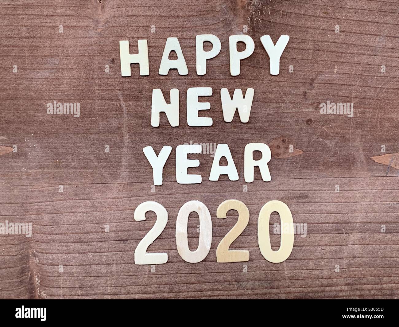 Happy New Year 2020 composed with wooden letters and numbers over a wooden board - Smartphone Captured Stock Image
